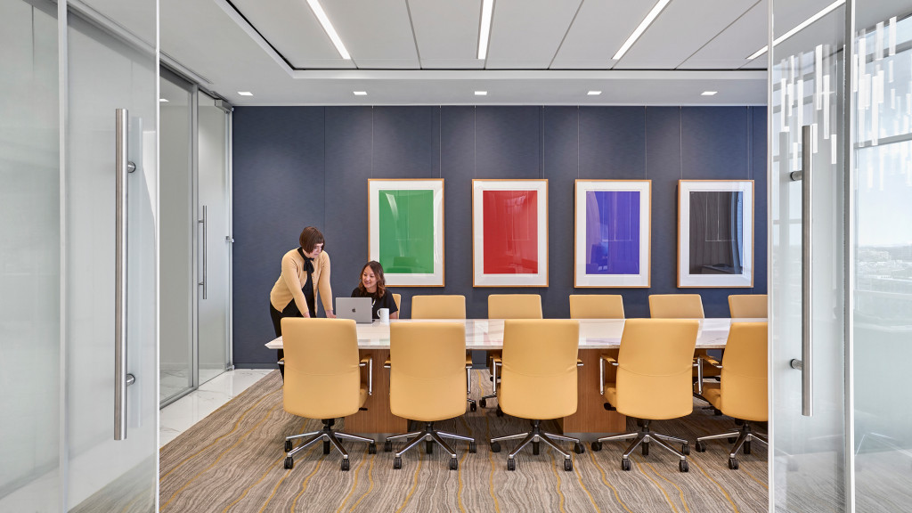 A person standing next to a table with chairs and a person sitting at it.